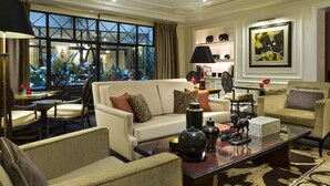 A well-lit living room with a large window, a sofa, armchairs, a coffee table, and a bookshelf. - Hôtel Francois 1er (Paris)
