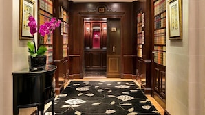 A hallway with a black and white patterned carpet, wooden paneling, and framed artwork on the walls. - Hôtel Francois 1er (Paris)