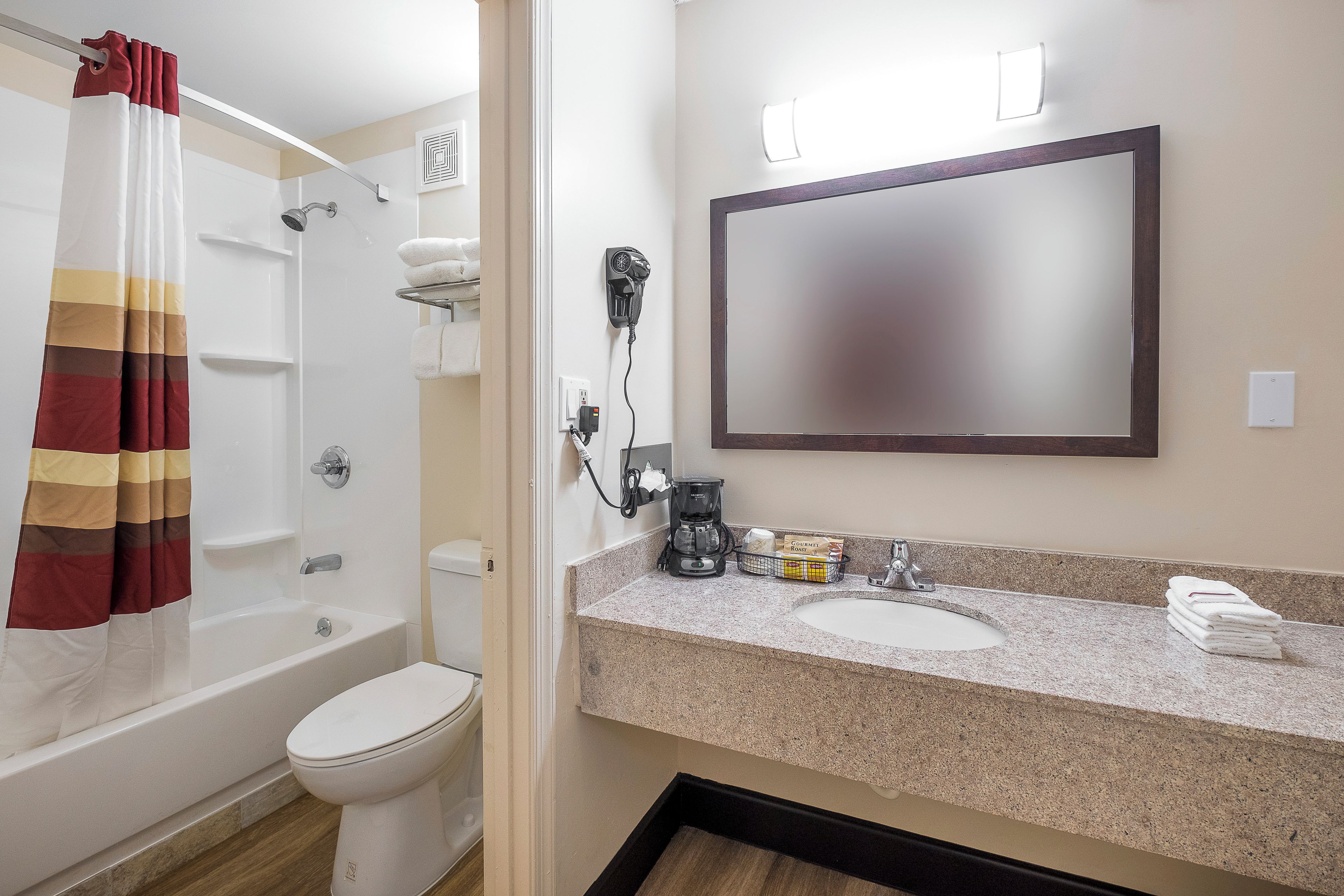A bathroom with a shower, toilet, and a sink with a mirror.
