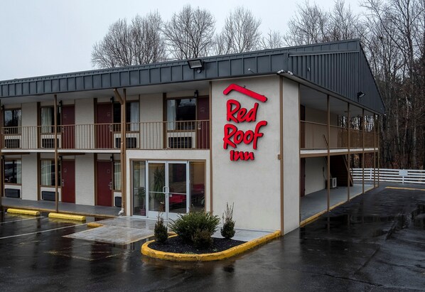 Un Red Roof Inn con una estructura de dos pisos, un área de estacionamiento techada y una entrada visible.