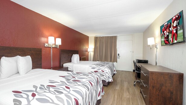 Een hotelkamer met een tweepersoonsbed, een bureau, een stoel, een televisie en een schilderij aan de muur.