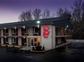Un hôtel Red Roof Inn avec une structure à deux étages, un espace de stationnement couvert et une entrée bien visible.