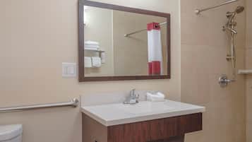 A bathroom with a white sink, a mirror, a towel rack, and a shower area.