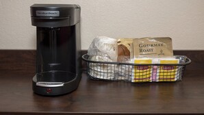 Una cafetera comercial Hamilton Beach y una cesta con sobres de café Gourmet Roast y una bolsa de plástico.