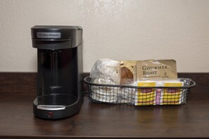 Una cafetera comercial Hamilton Beach y una cesta con sobres de café Gourmet Roast y una bolsa de plástico.
