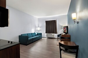 Una sala de estar moderna con un sofá, una mesa de madera, un televisor y una lámpara de pared.