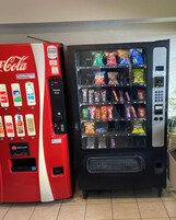 Two vending machines, one with a Coca-Cola logo and the other with a variety of snacks.