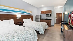 A hotel room with two beds, a kitchenette, a TV, and a painting on the wall. - HomeTowne Studios by Red Roof East Lansing - Okemos (Okemos)