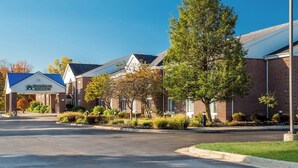 A row of brick buildings with a sign for Home Rowne Studios. - HomeTowne Studios by Red Roof East Lansing - Okemos (Okemos)
