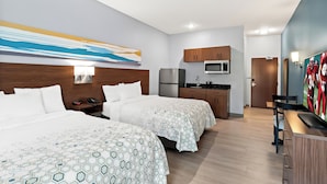 A hotel room with two beds, a kitchenette, a TV, and a painting on the wall.