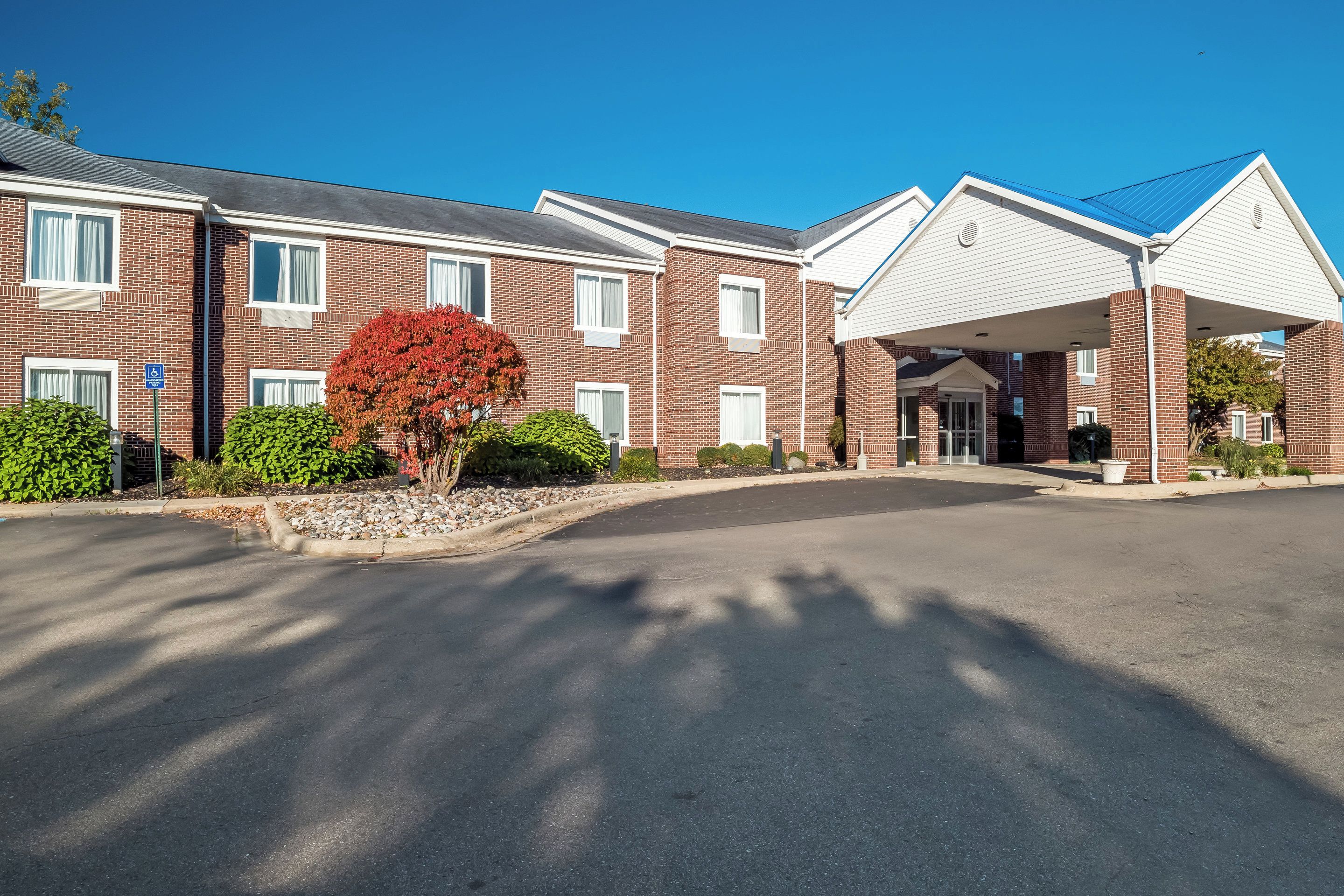 A multi-story brick building with a covered entrance and a parking lot.