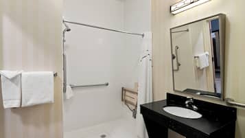 Un baño con ducha a nivel, lavamanos y espejo.