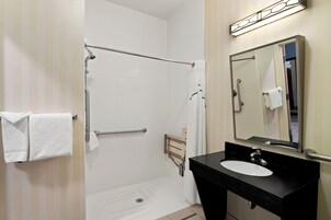 Un baño con ducha a nivel, lavamanos y espejo.