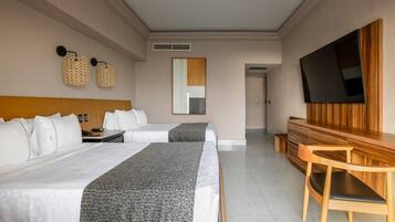 Una habitación de hotel con dos camas, un escritorio, un televisor y un espejo.