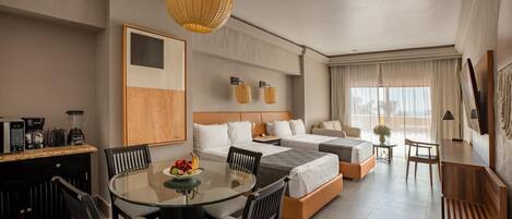 A hotel room with a bed, two bedside tables, a desk with a chair, a round dining table with chairs, and a hanging light fixture.
