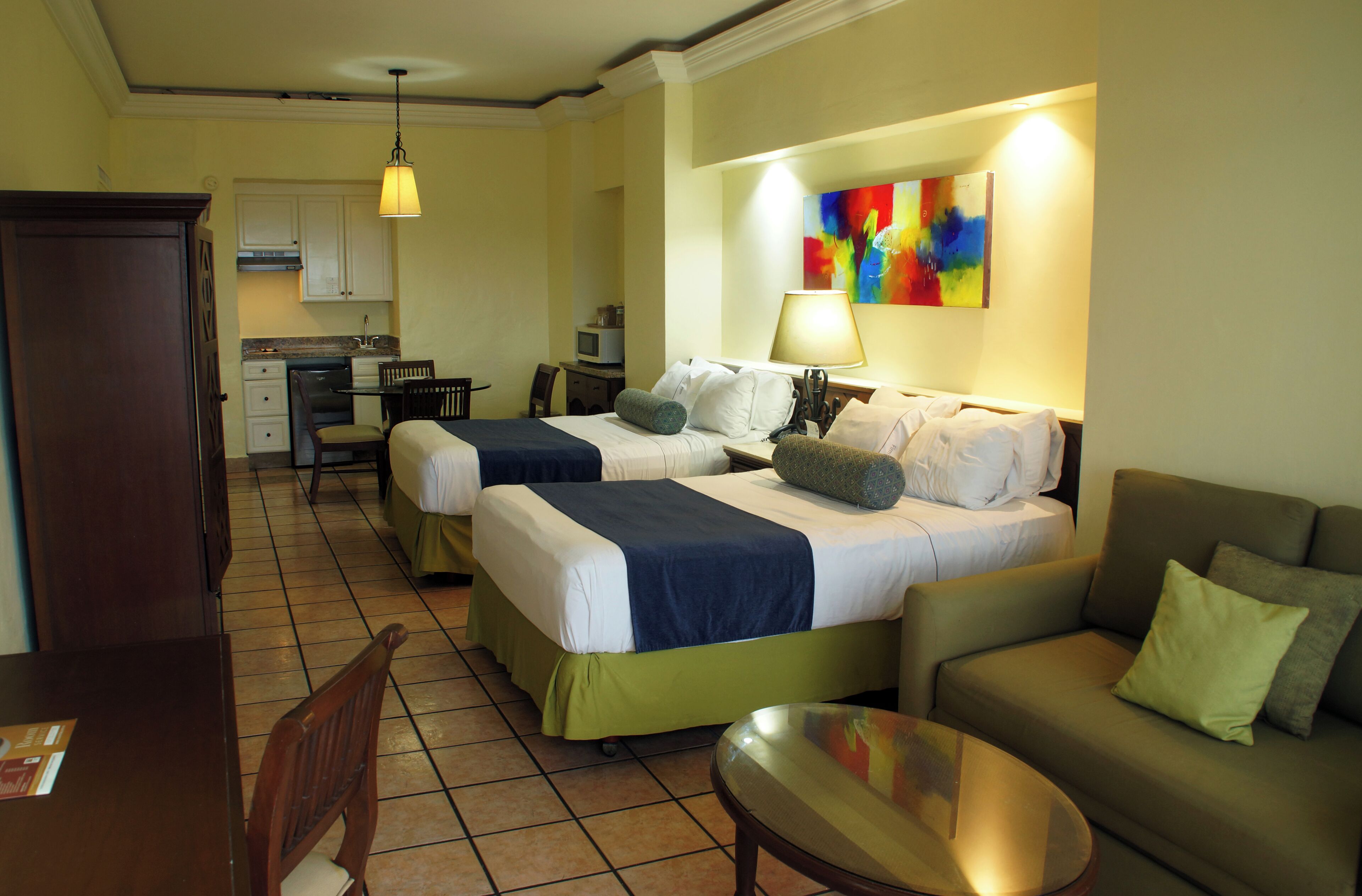 Une chambre d’hôtel avec deux lits, un canapé, une table à manger et une kitchenette.