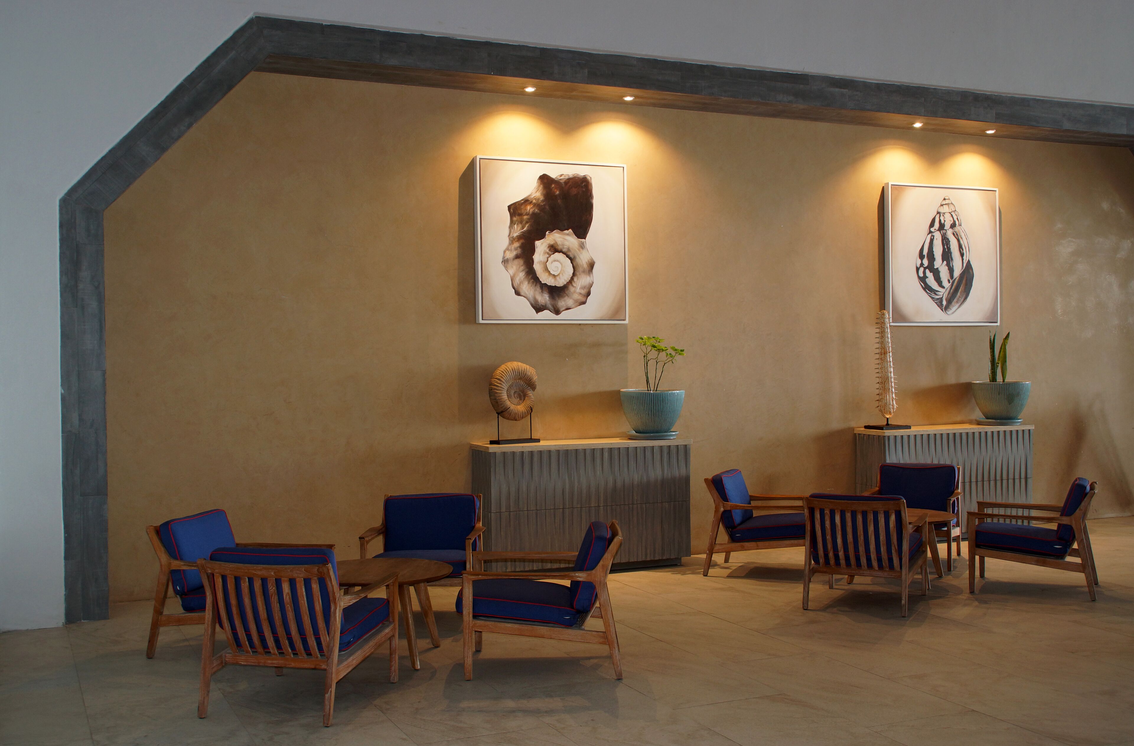 A lobby with wooden chairs and sofas, a reception desk, and two framed artworks on the wall.