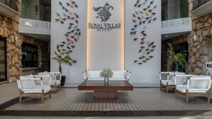 A lobby with a central seating area, a stone wall, and a sign for Royal Villas Resort. - Royal Villas Resort (Mazatlán)