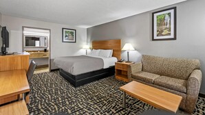 A hotel room with a bed, a sofa, a desk, and a TV. - Quality Inn Bowling Green South (Bowling Green)