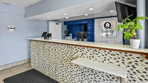A hotel reception desk with a mosaic-patterned counter, a Dell computer, and a sign that reads "Quality by Choice Hotels". - Quality Inn Bowling Green South (Bowling Green)