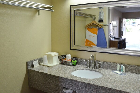 A hotel bathroom with a granite countertop, sink, and mirror.