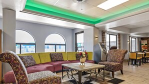A hotel lobby with a sofa, chairs, a table, and a view of the city through large windows. - Quality Inn Bowling Green South (Bowling Green)