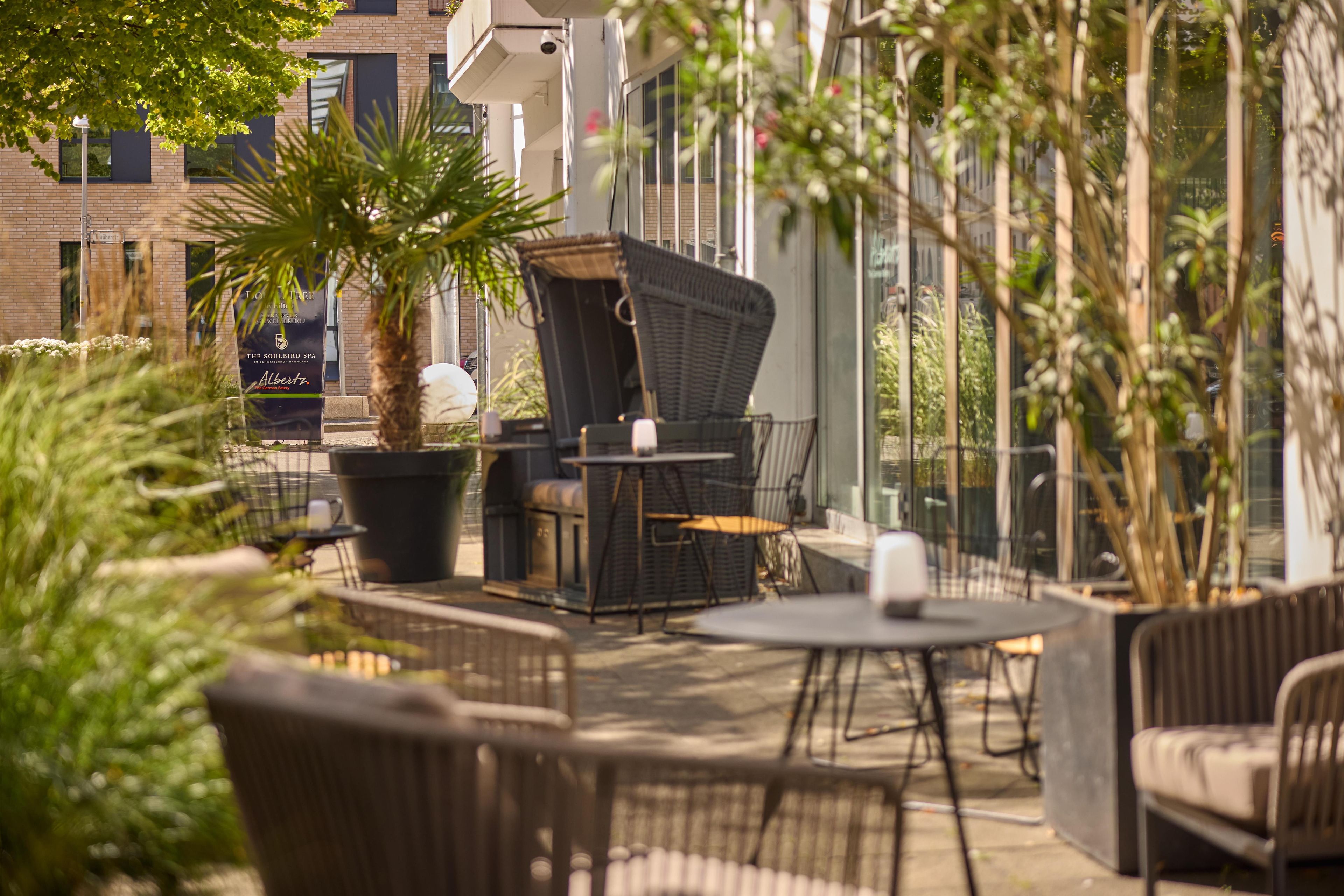 An outdoor seating area with wicker furniture, a large potted plant, and a sign for The Soulbird Spa.