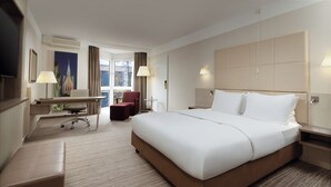 Habitación de hotel con una cama grande, un escritorio, una silla y un televisor.