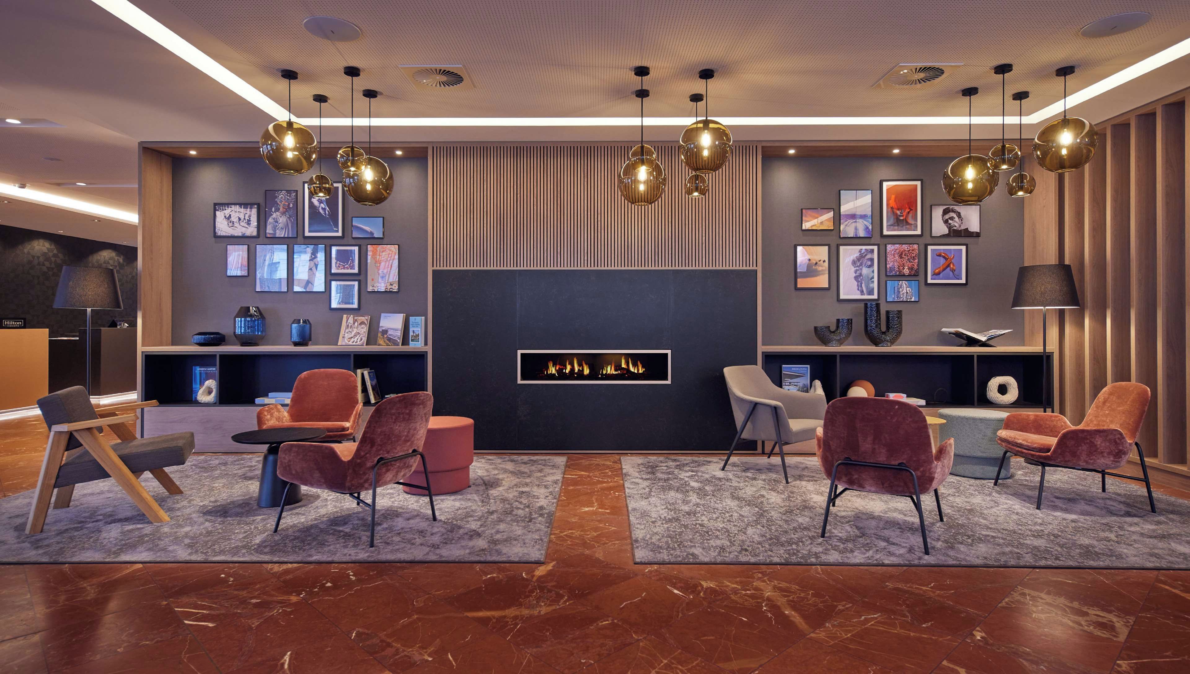 A modern hotel lobby with a fireplace, comfortable seating, and artwork on the walls.