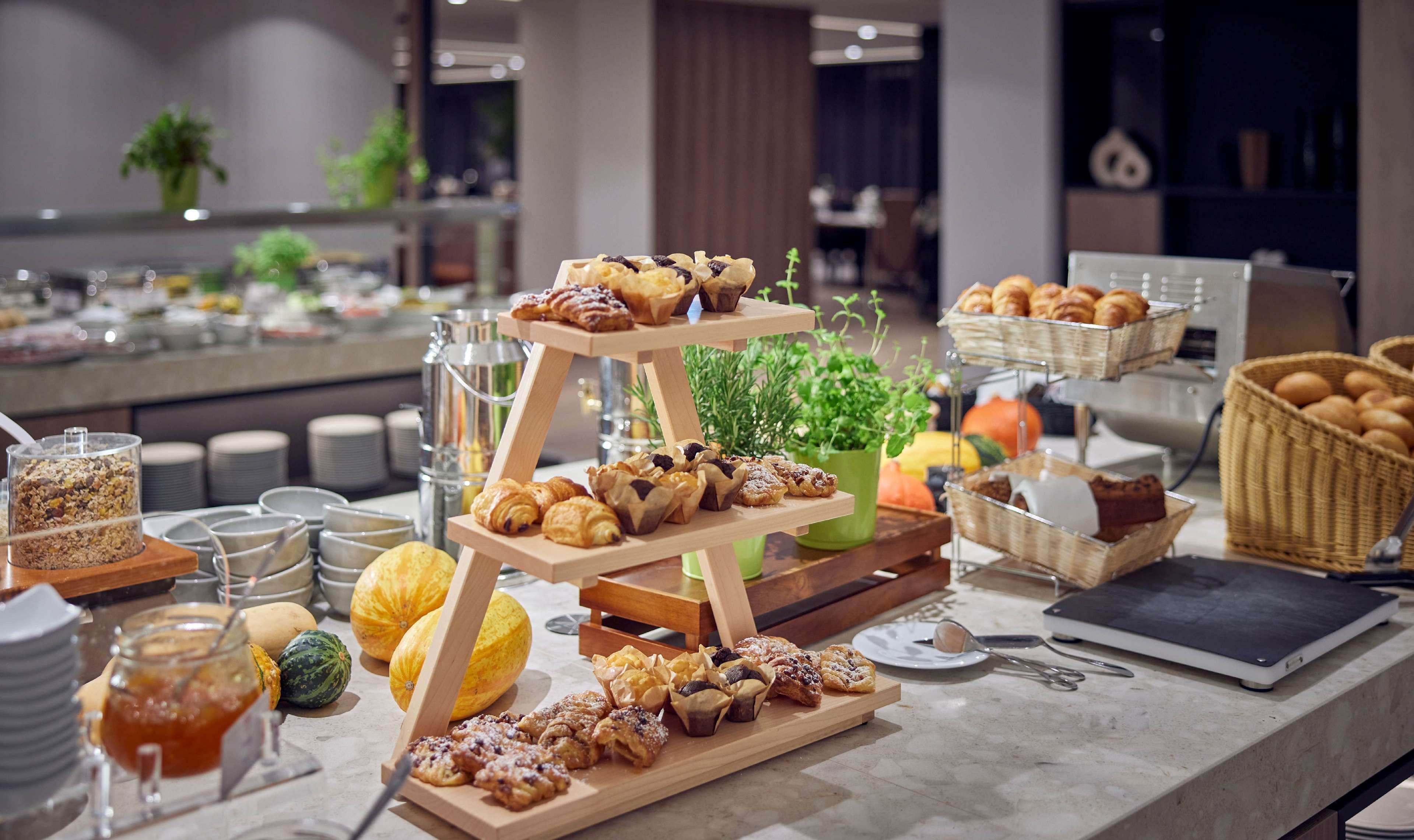 A buffet setup with various pastries, fruits, and a laptop on a table.