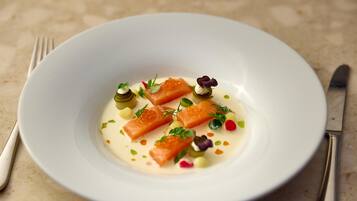 A white plate with salmon, cream, and garnishes on a textured surface.