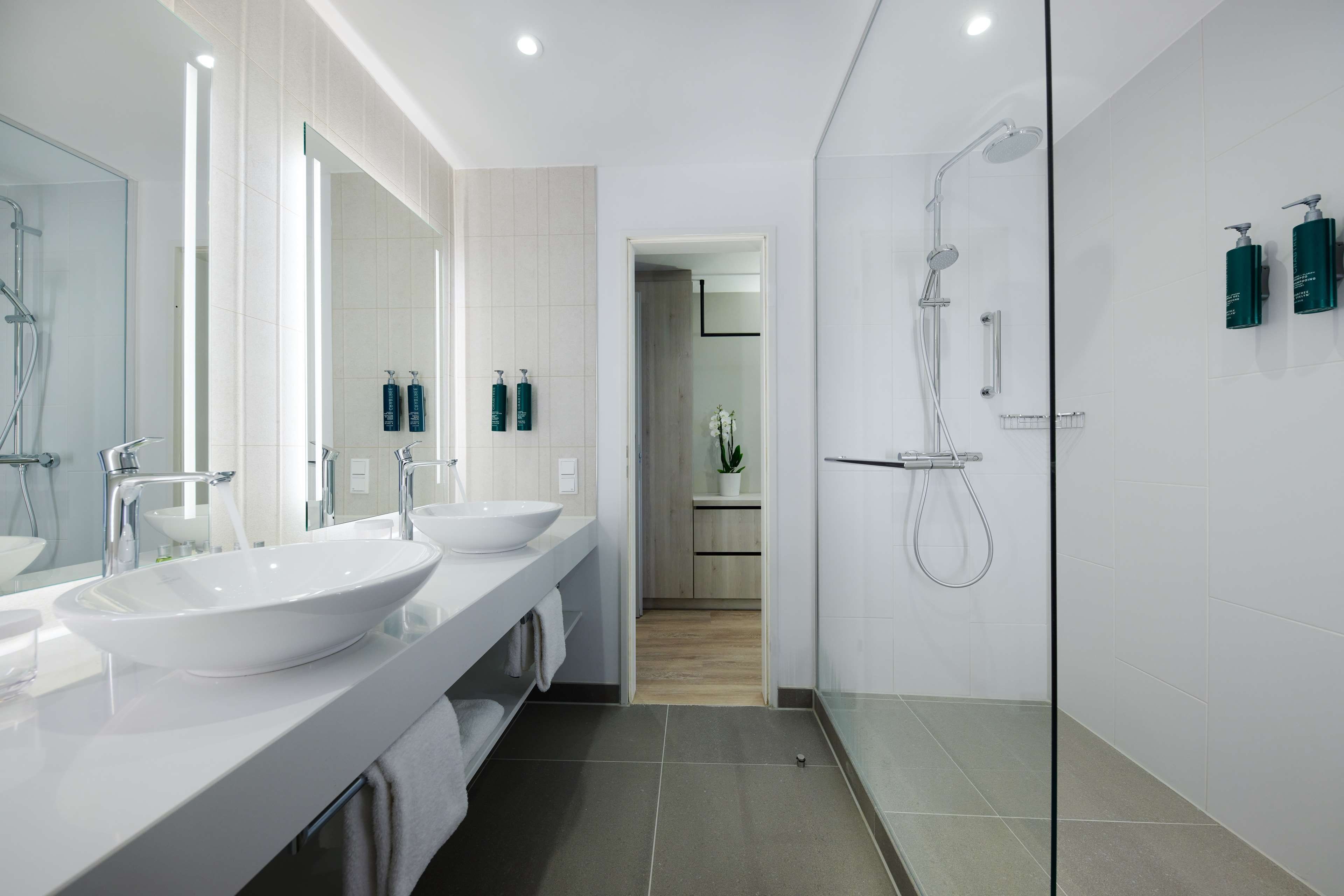A modern bathroom with two sinks, a glass shower enclosure, and a walk-in shower.
