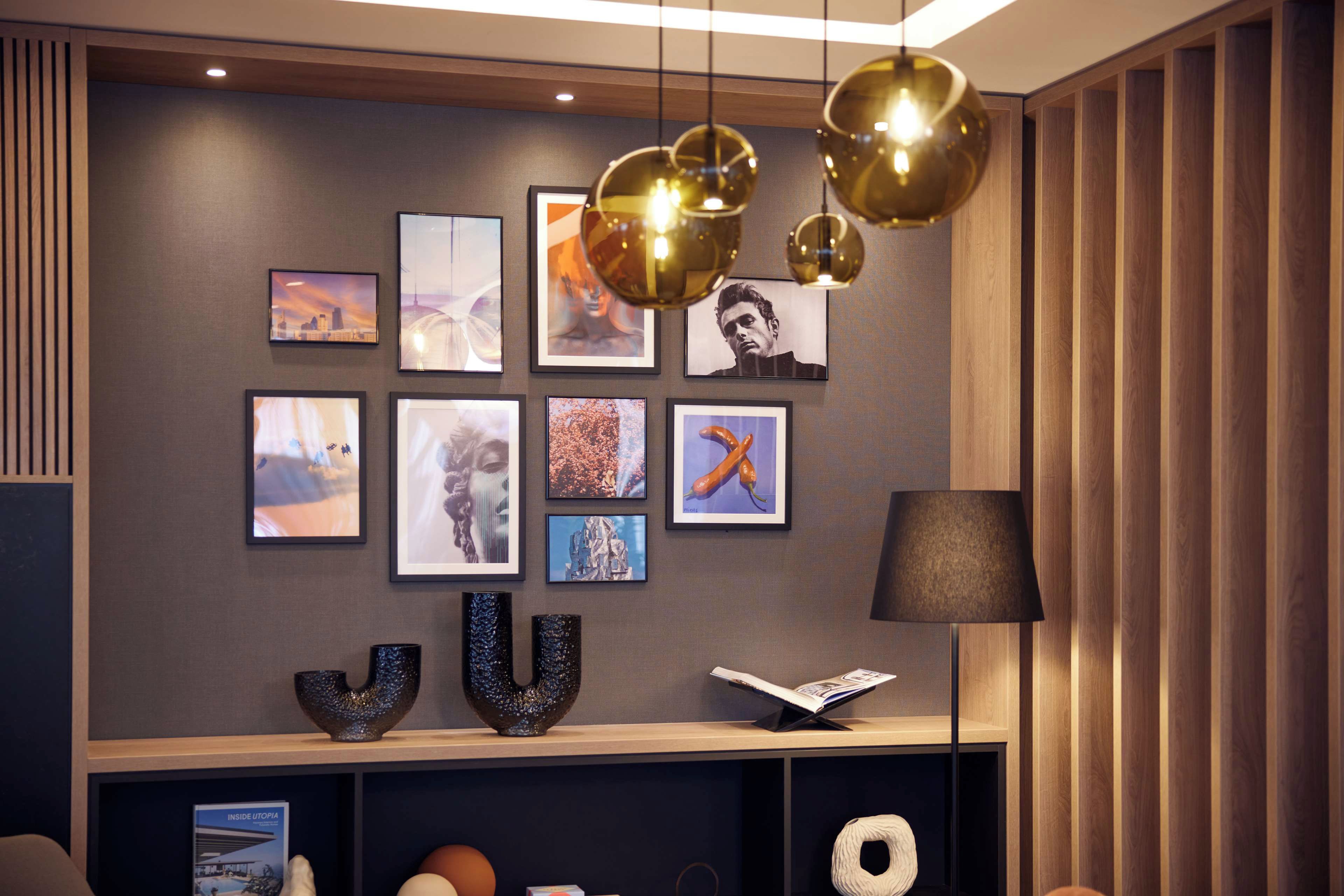 A modern interior with a wall adorned with framed photographs, a decorative bowl, and a lamp.