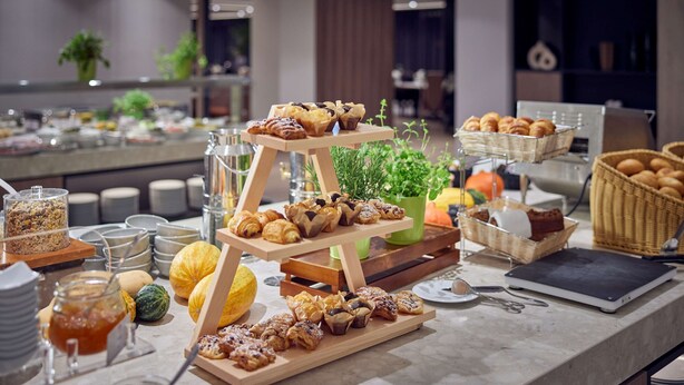 A buffet setup with various pastries, fruits, and a laptop on a table. - DoubleTree by Hilton Hannover Schweizerhof (Hannover)