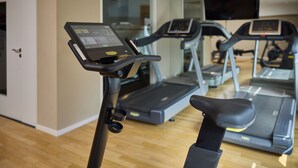 Un gimnasio con cintas de correr y una bicicleta estática.