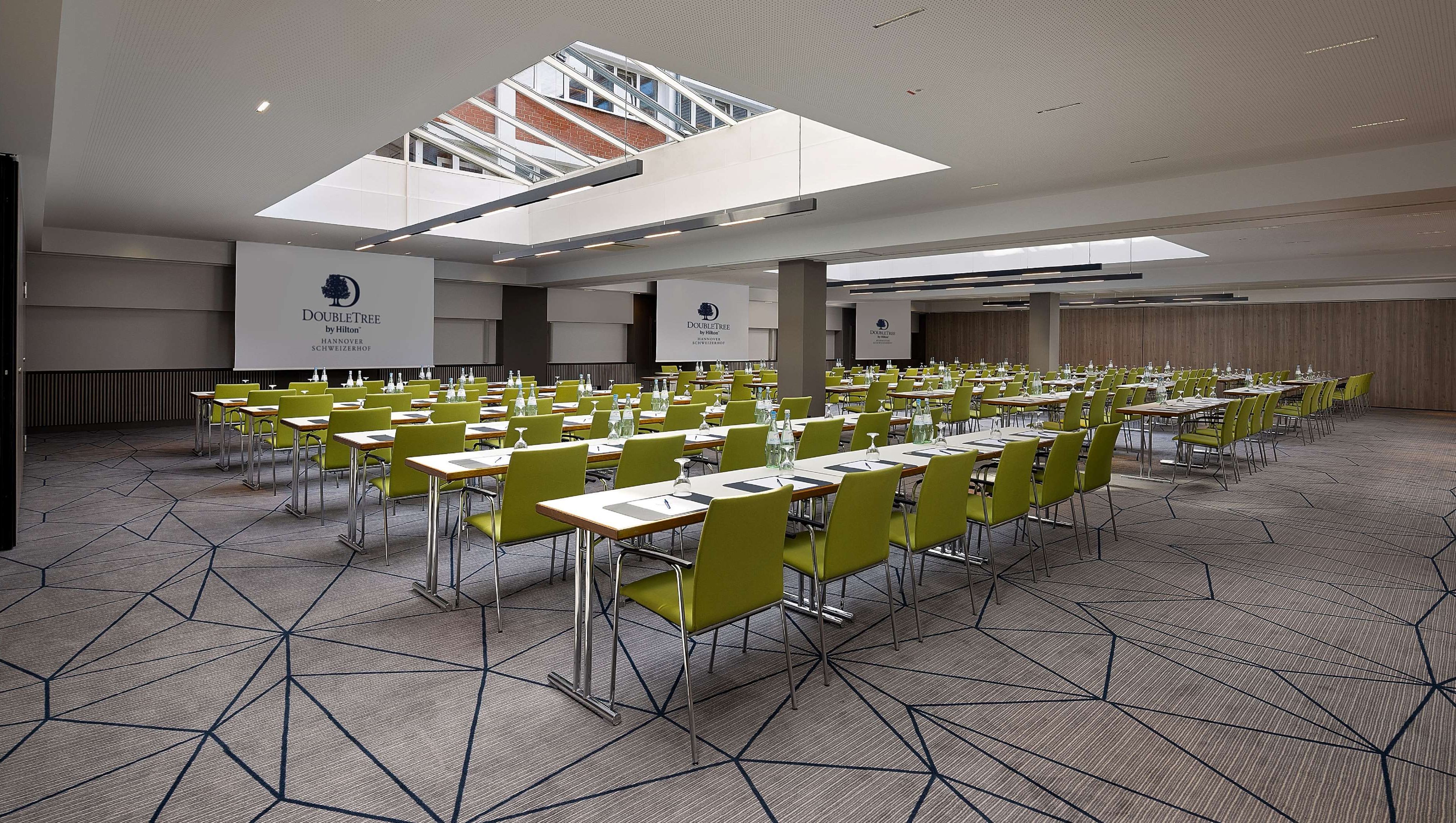 Un salón de conferencias con varias mesas y sillas dispuestas en filas.