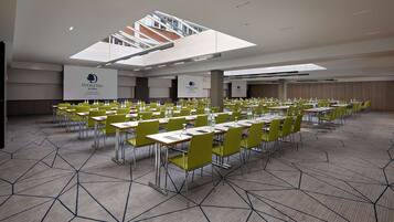Un salón de conferencias con varias mesas y sillas dispuestas en filas.