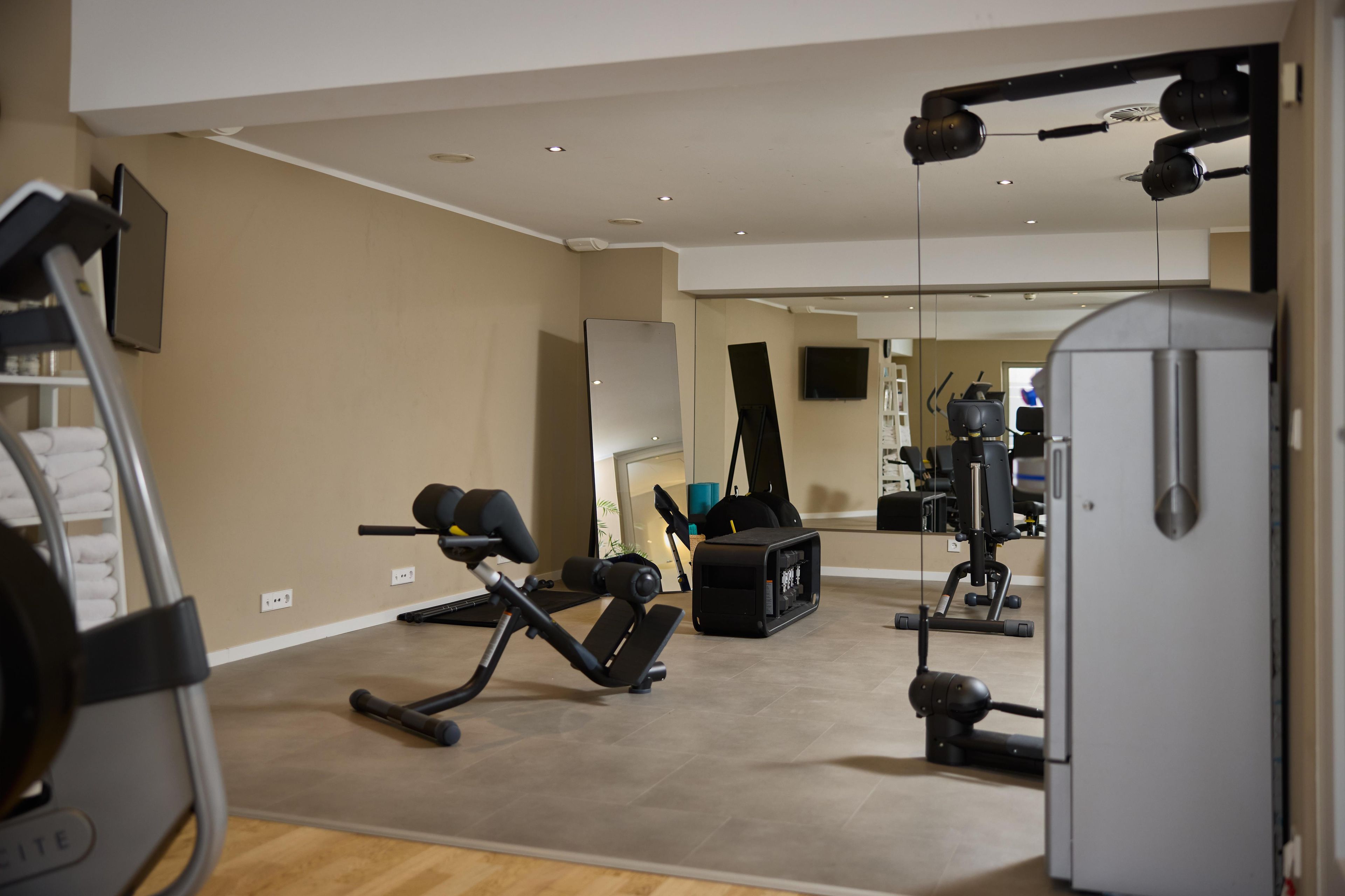 A home gym with exercise equipment, a treadmill, and a mirror.