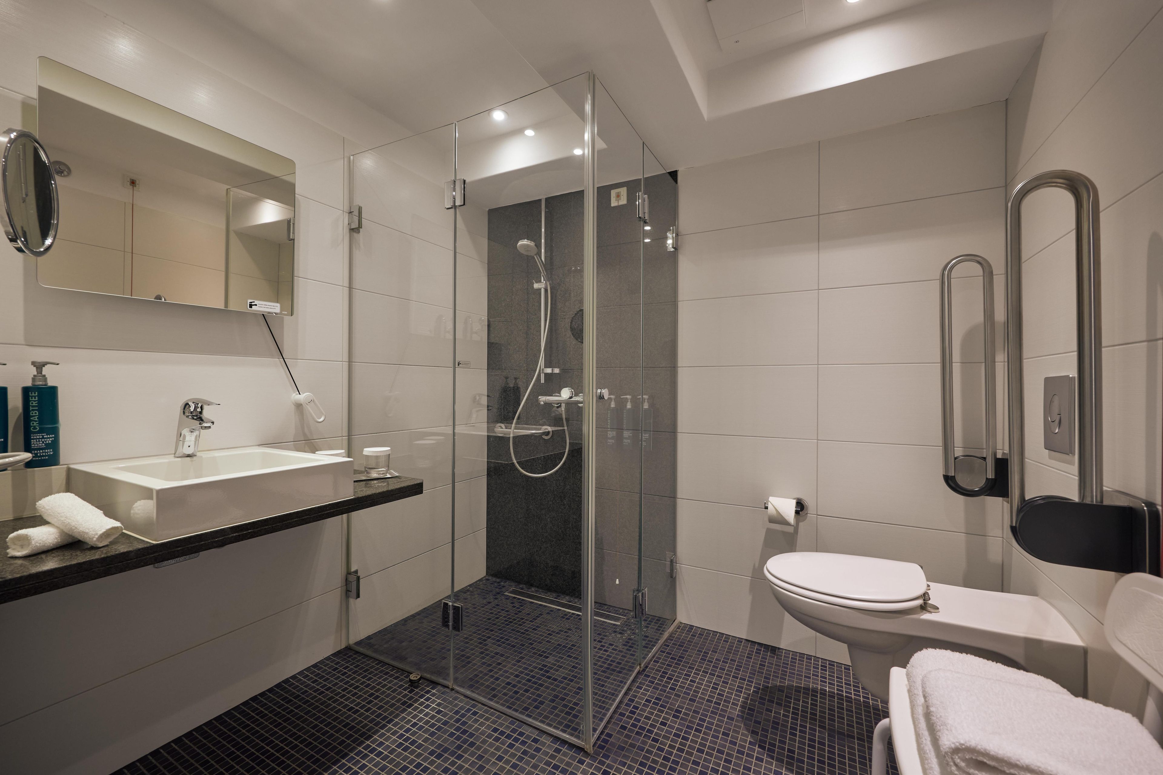 A modern bathroom with a glass-enclosed shower, a white sink, and a toilet.