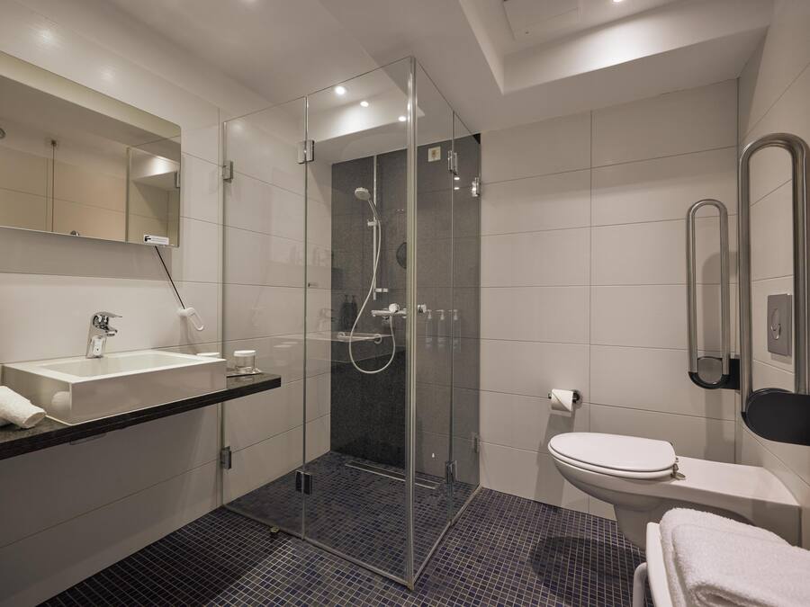 A modern bathroom with a glass-enclosed shower, a white sink, and a toilet.