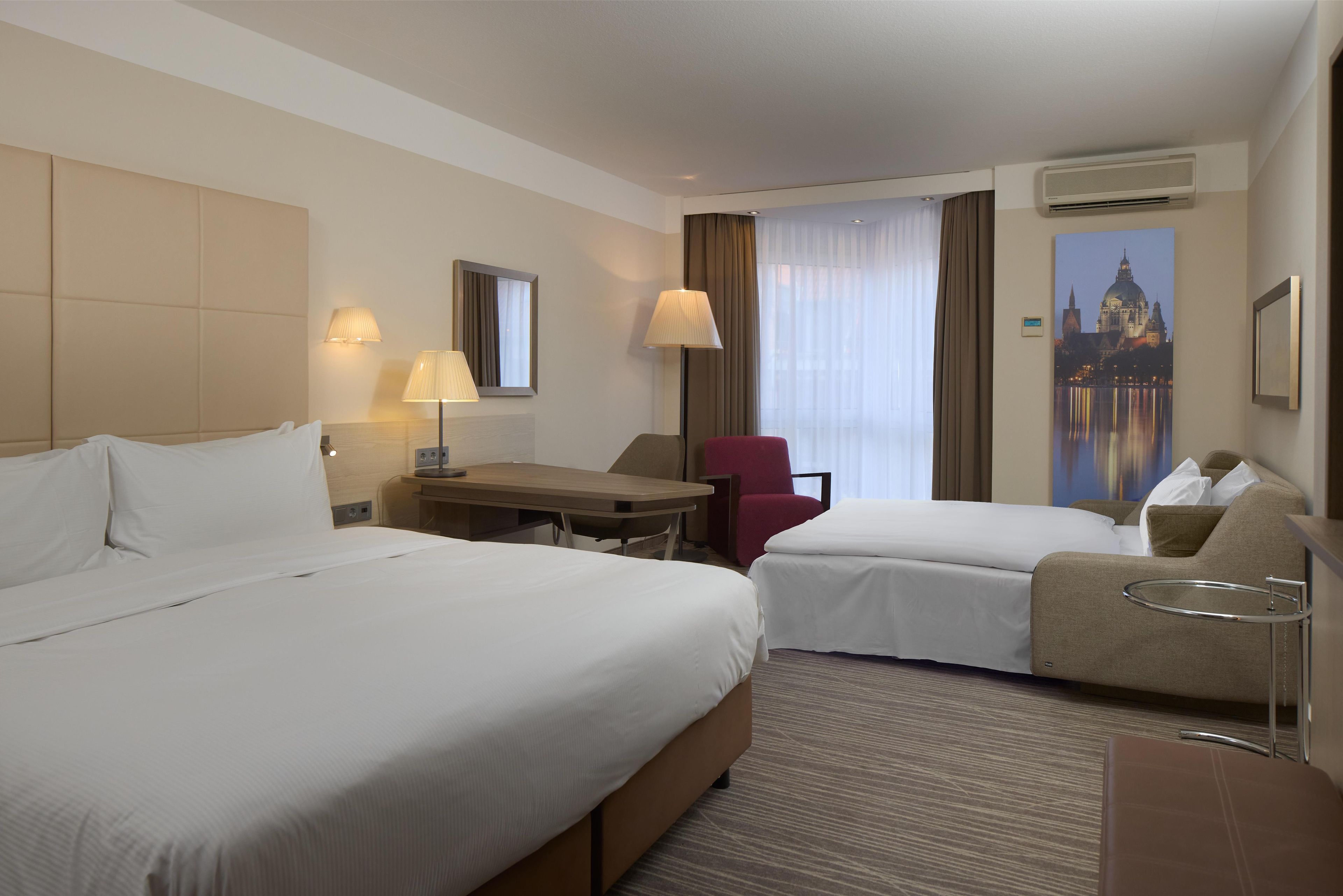 Una habitación de hotel con dos camas, un escritorio, una silla y un sofá.