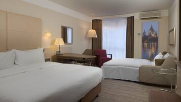 Una habitación de hotel con dos camas, un escritorio, una silla y un sofá.