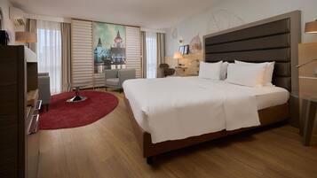 Ein Hotelzimmer mit einem großen Bett, einem Schreibtisch, einem Sessel, einem roten Teppich und einem Stadtbild an der Wand.
