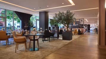Un interior de restaurante moderno con zona de comedor, barra y vista a la calle.