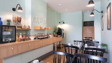 A cafe with a wooden counter, black chairs, and a coffee machine.