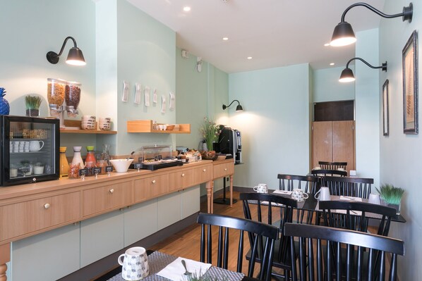 A cafe with a wooden counter, black chairs, and a coffee machine.