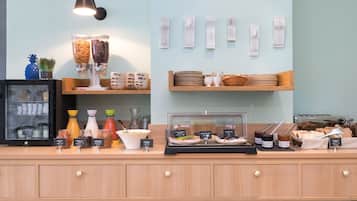 Una colazione a buffet con diversi cibi e condimenti, una macchina da caffè e un espositore di utensili a parete.