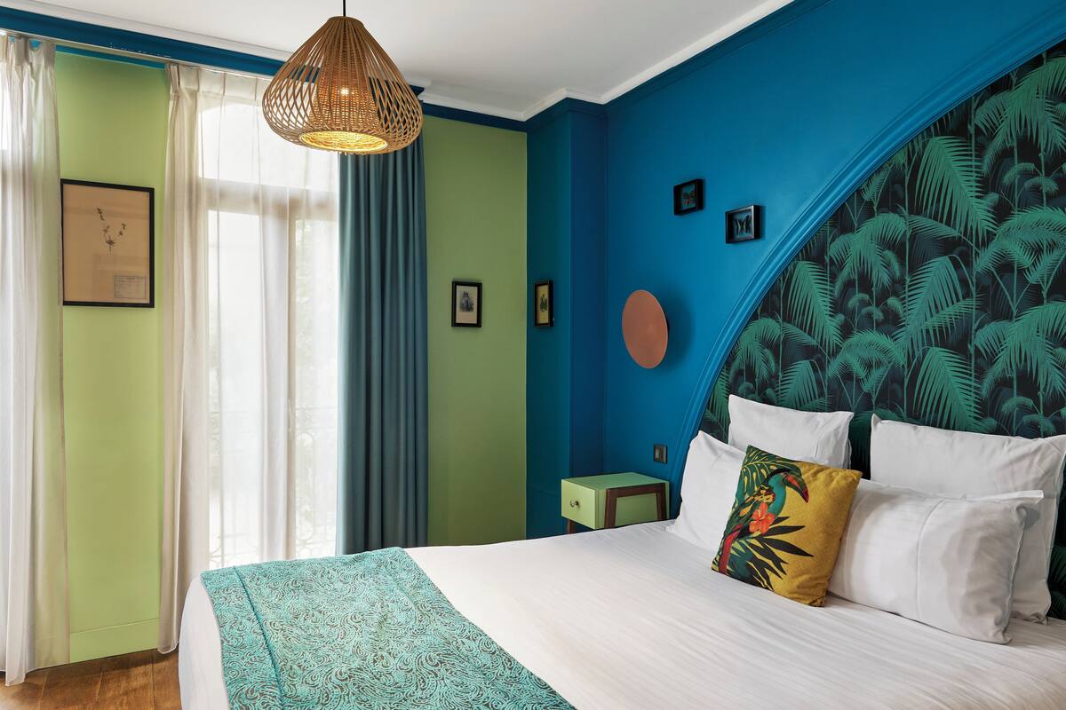 Un dormitorio con cama, mesita de noche y lámpara colgante.