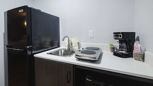 A compact kitchen with a black refrigerator, a sink, a coffee maker, and a small countertop area. - SureStay by Best Western Channelview Houston East (Channelview)