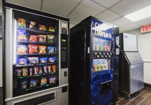 Máquinas expendedoras con aperitivos y bebidas, un refrigerador y una señal de salida.